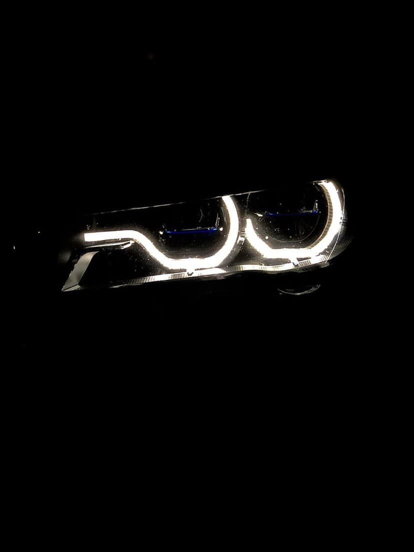 BMW Angel Eye LED rings glowing white against a black background with sharp reflections on the headlight housing.