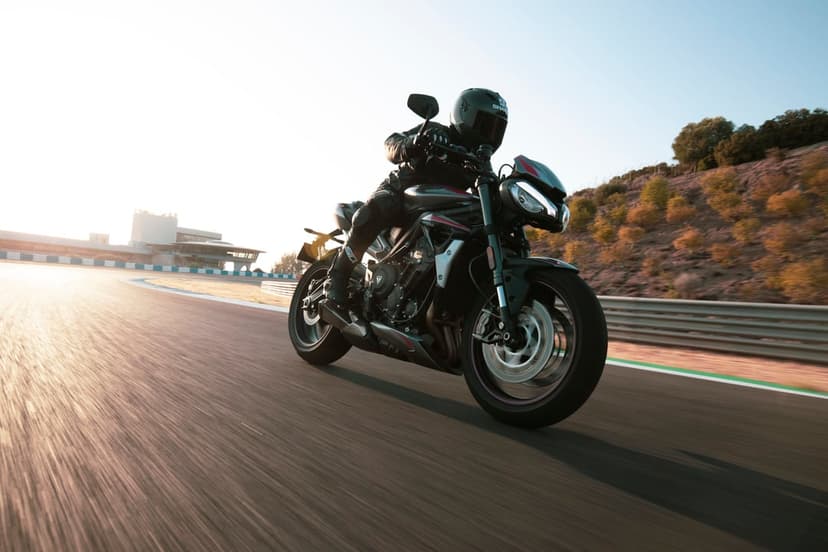Black motorcycle leaning into a racetrack turn at sunset with motion blur and warm golden sunlight.