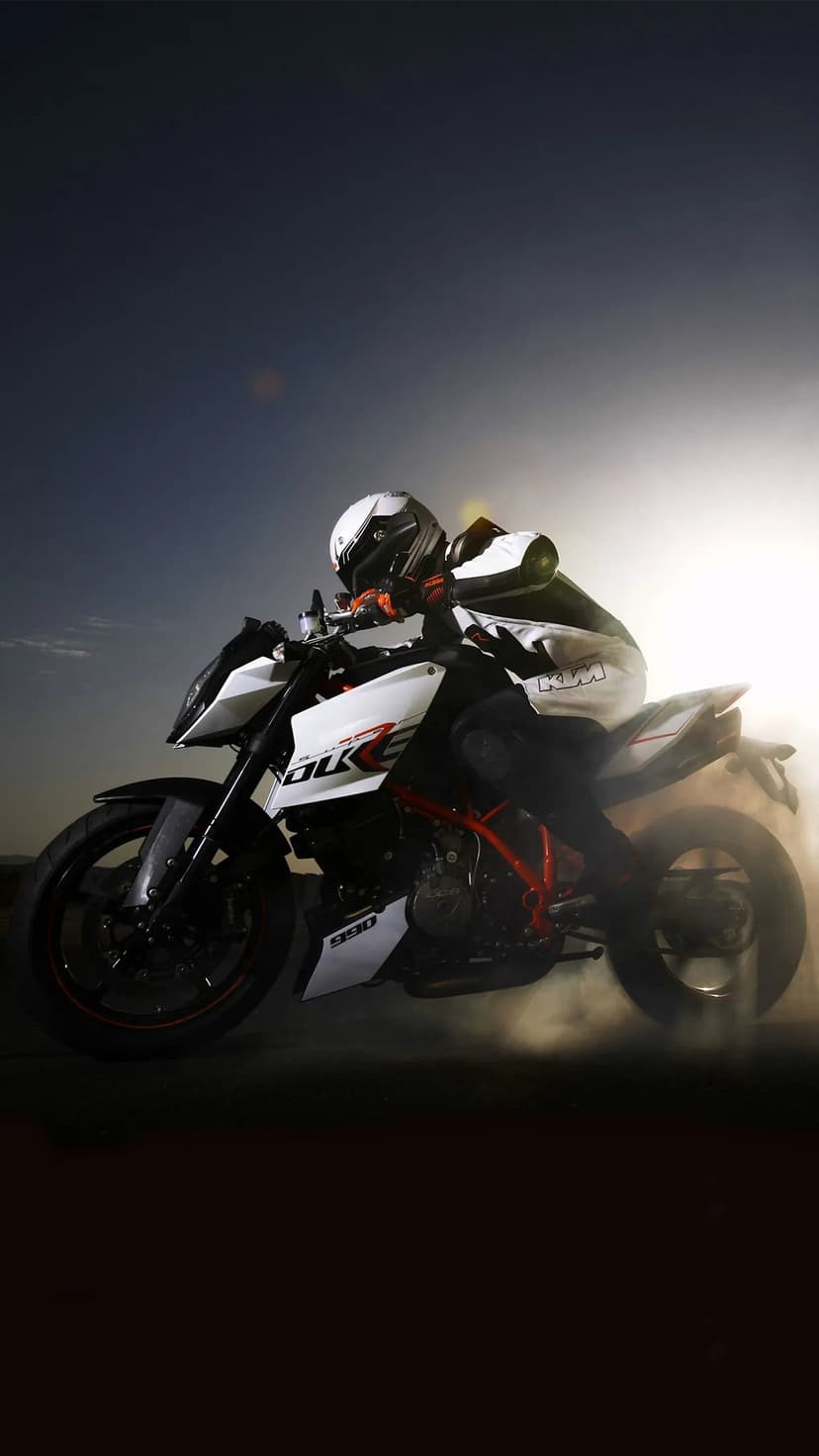 White KTM Super Duke R motorcycle performing a smoky burnout with intense backlighting and a dark sky.