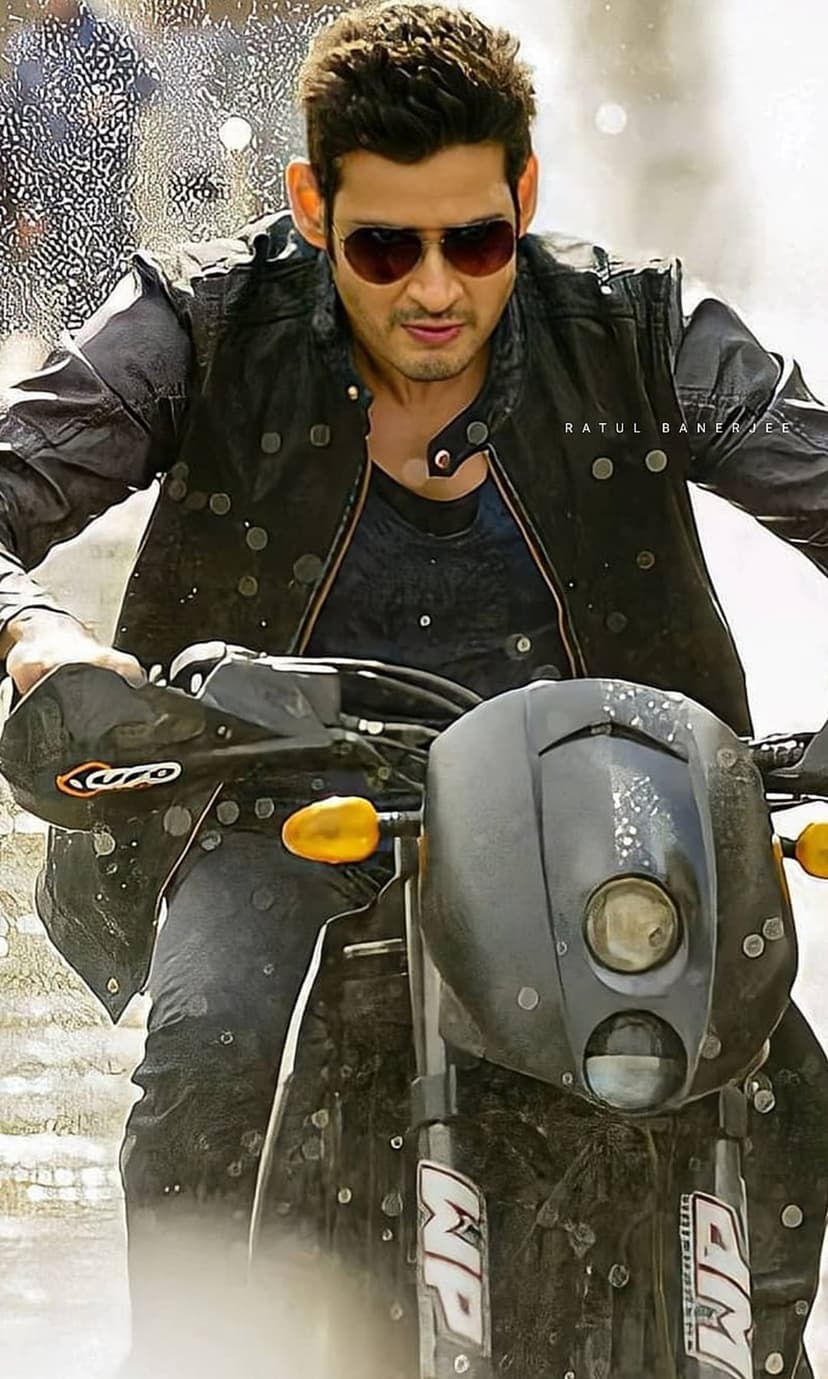 Mahesh Babu rides a motorcycle wearing a black leather jacket and sunglasses with an intense, focused expression.