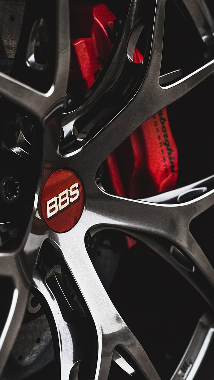 BBS alloy wheel spokes focus on a red center logo and crimson brake calipers with polished metallic surfaces.