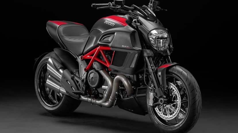 Ducati Diavel Carbon motorcycle with red trellis frame and metallic exhaust pipes on a black backdrop.
