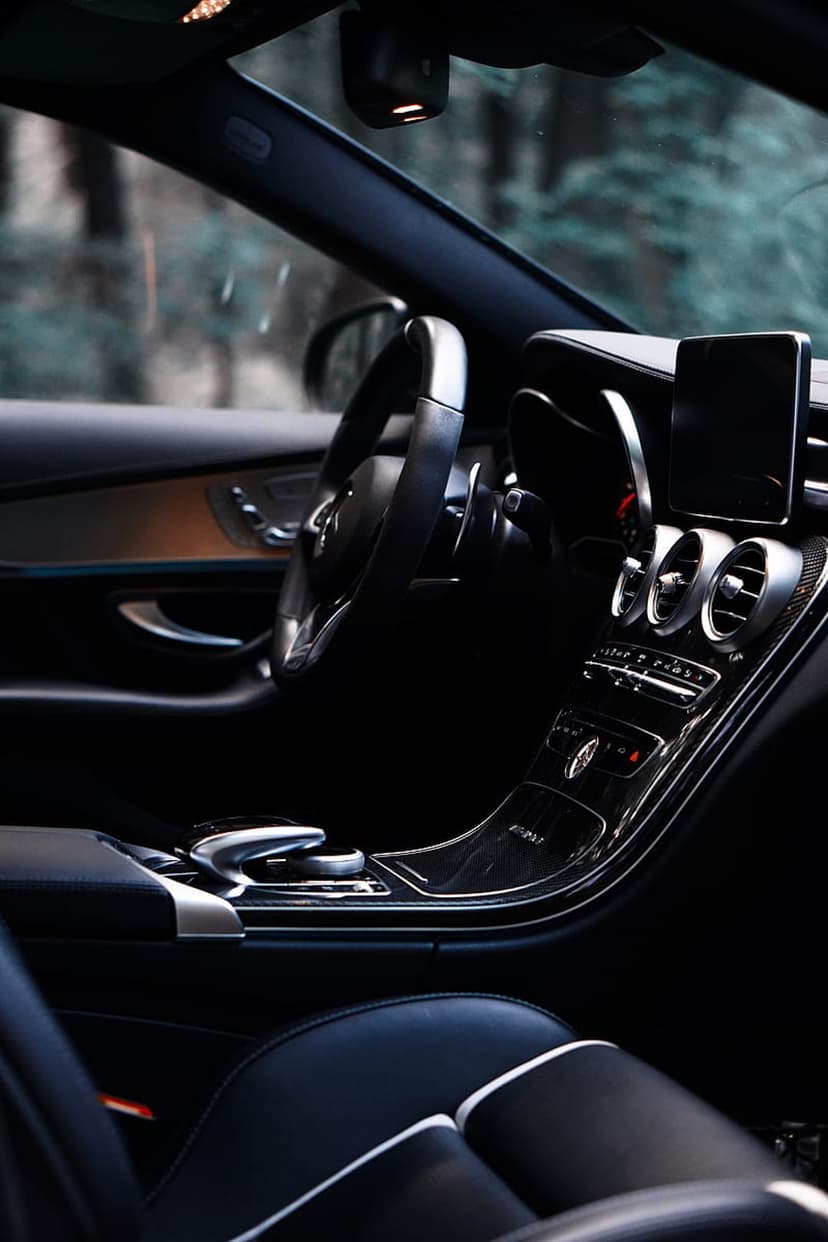 Leather-wrapped steering wheel and glowing digital dashboard display inside a high-end luxury vehicle interior.