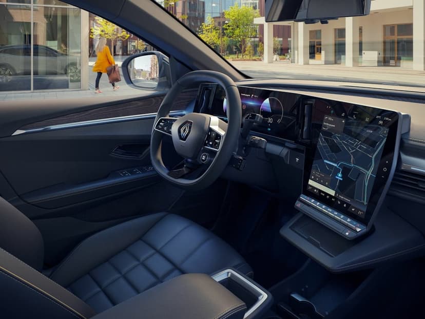 Car interior with a digital dashboard, steering wheel, and quilted leather seats overlooking a city street.