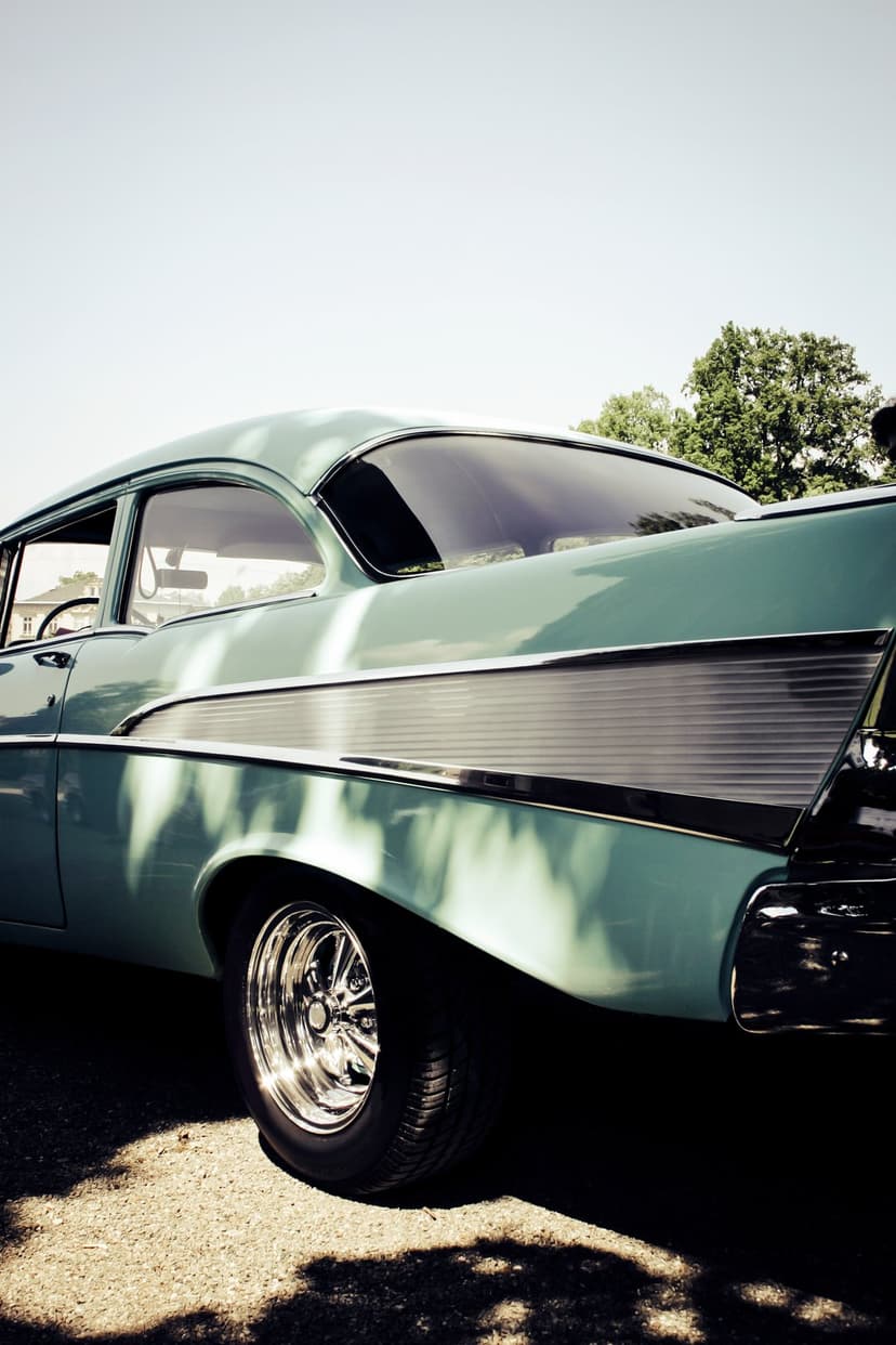 1957 Chevrolet Bel Air rear quarter with teal paint, chrome tail fins, and sunlit metallic details.