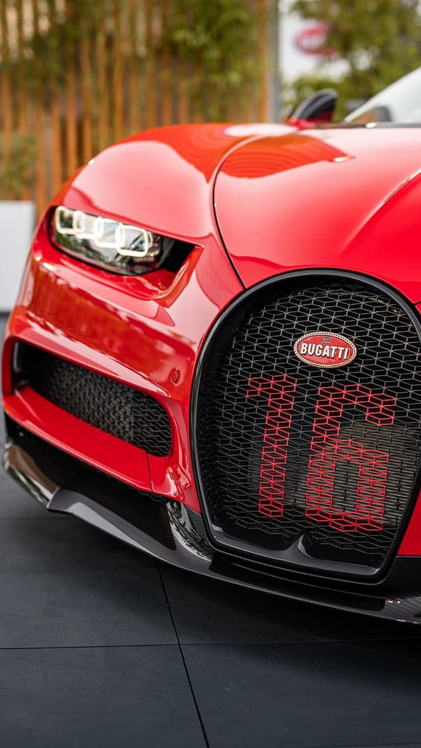 Red Bugatti Chiron horseshoe grille with black mesh and illuminated 300+ lettering in a close-up shot.