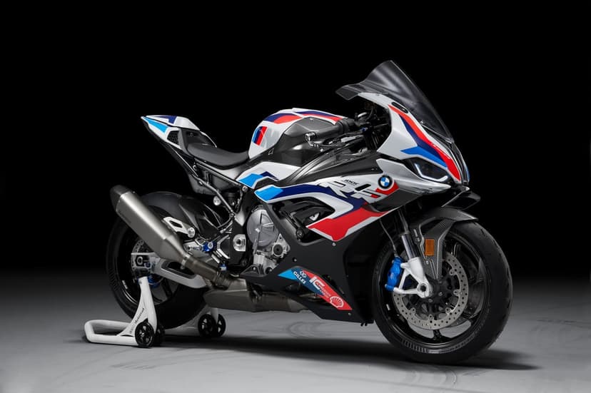 BMW M 1000 RR sportbike with M racing colors and carbon fiber fairings on a stand against a black background.