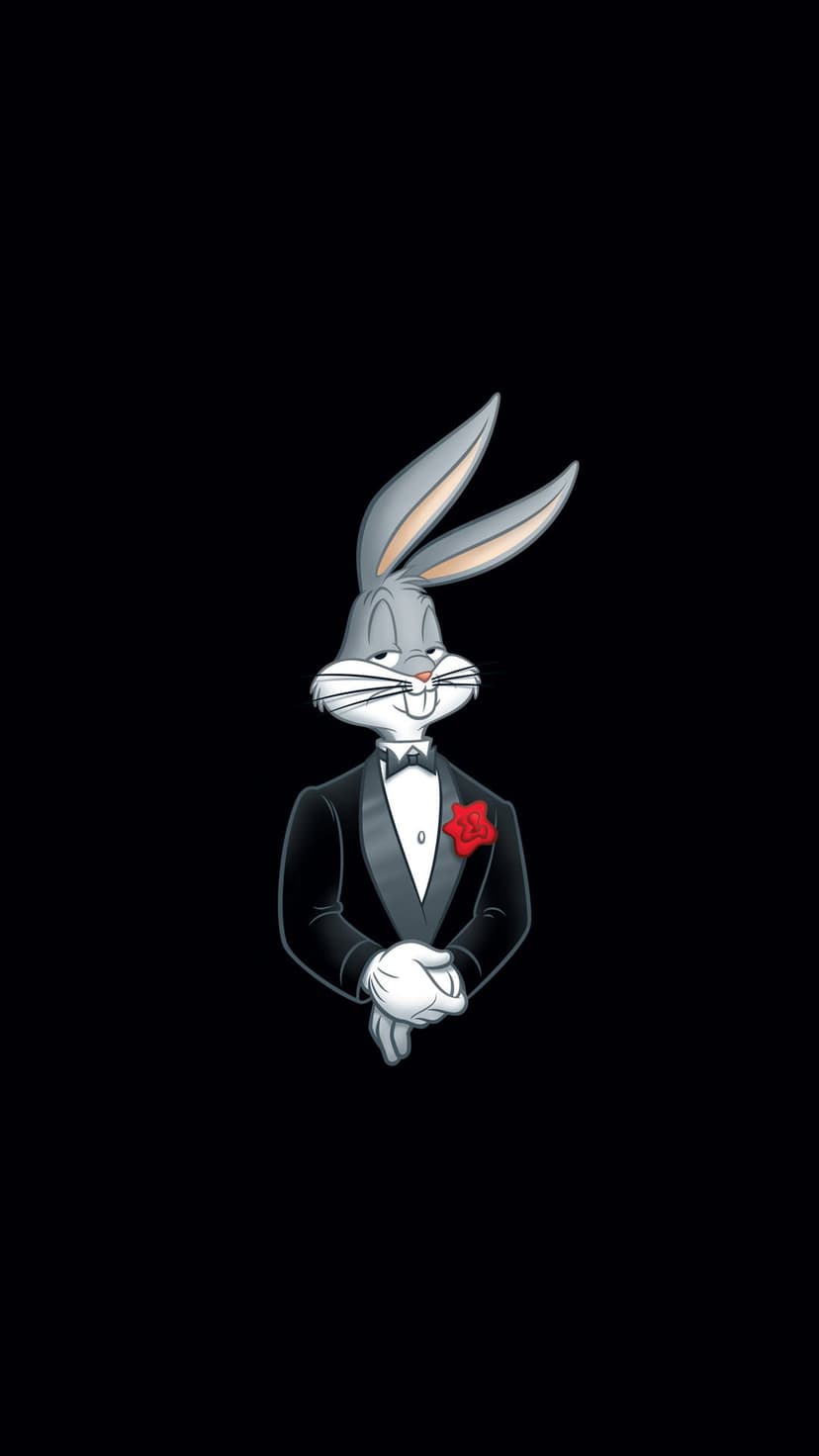 Bugs Bunny wears a formal black tuxedo with a red rose on the lapel while standing against a dark background.
