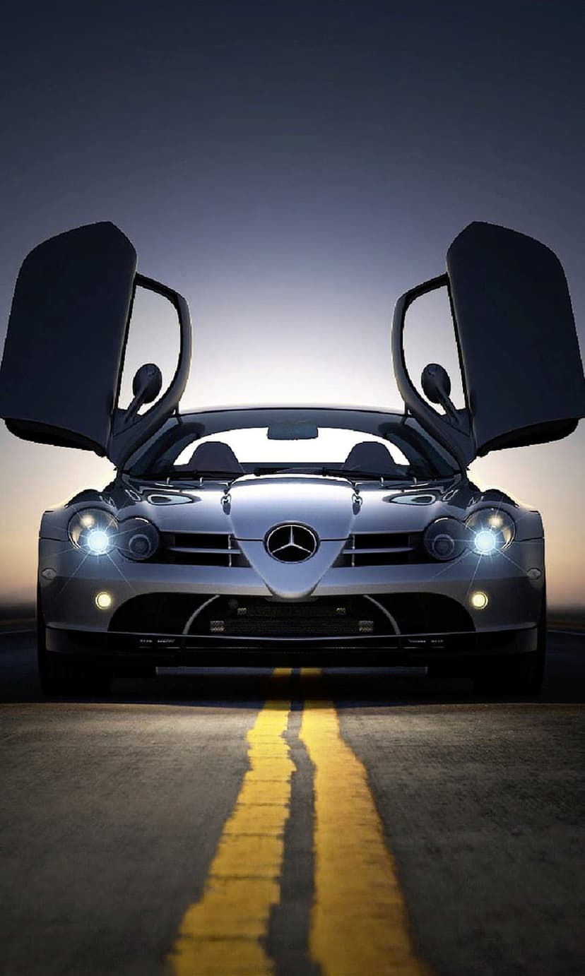 Silver Mercedes-Benz SLR McLaren Roadster with open gullwing doors parked on a dark road during twilight.