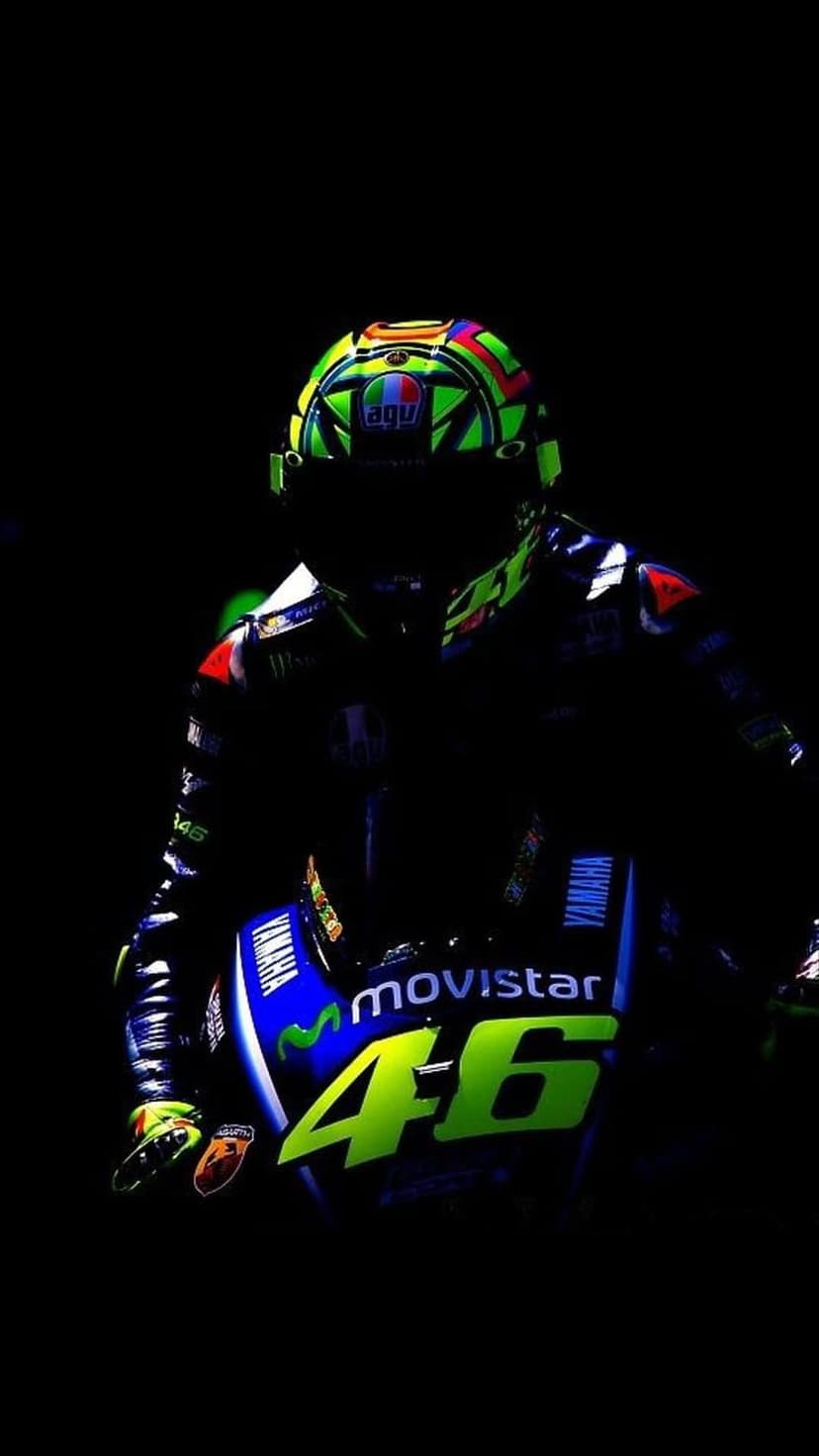 AGV racing helmet with colorful graphics sits above a Yamaha motorcycle featuring the number 46 in neon yellow.