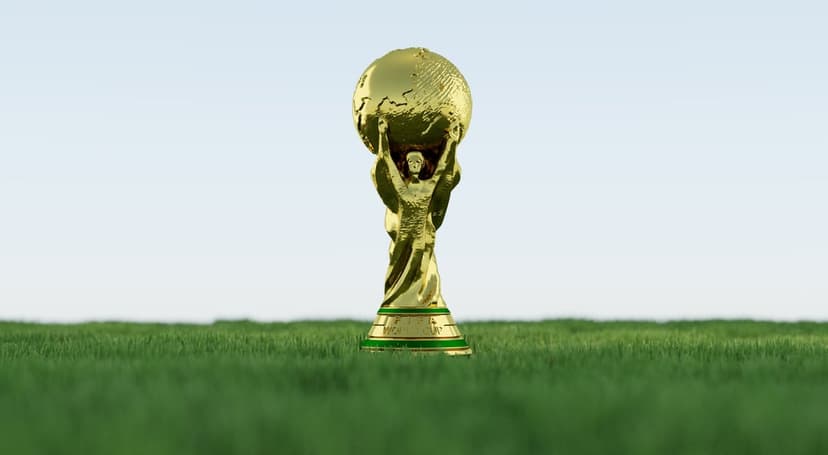 Polished gold world cup trophy positioned on vibrant green soccer turf under a bright, clear summer sky.