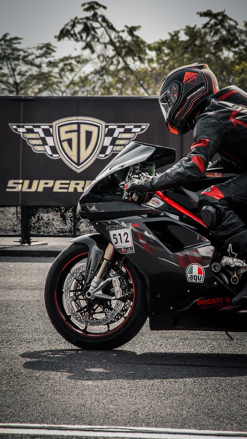 Ducati racing motorcycle with rider number 512 leaning into a turn on a paved track with SD Superbike logo behind.