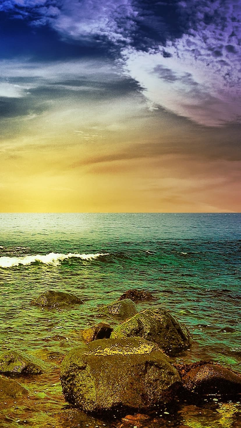 Weathered ocean rocks withstand crashing emerald waves beneath a gradient sky of orange, purple, and blue.