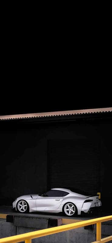 White Toyota Supra parked in dark industrial setting