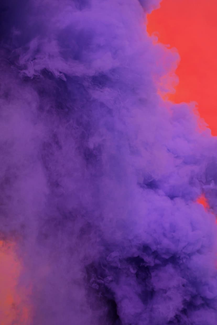 Purple smoke plumes swirl and intertwine against a solid, brightly lit orange background with soft lighting.