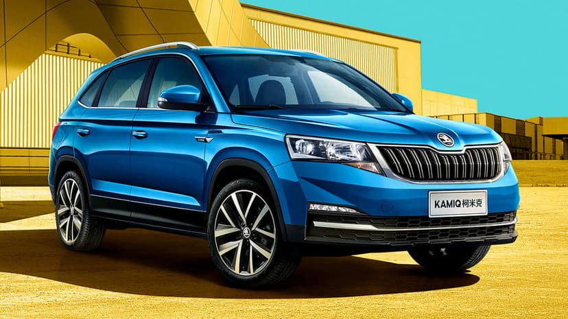 Blue SUV parked in front of a bright yellow geometric building under a clear blue sky with modern wheels.