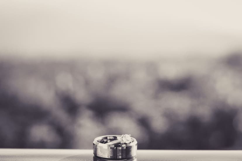 Two wedding rings with a visible diamond sparkle on a reflective surface against a soft bokeh background.