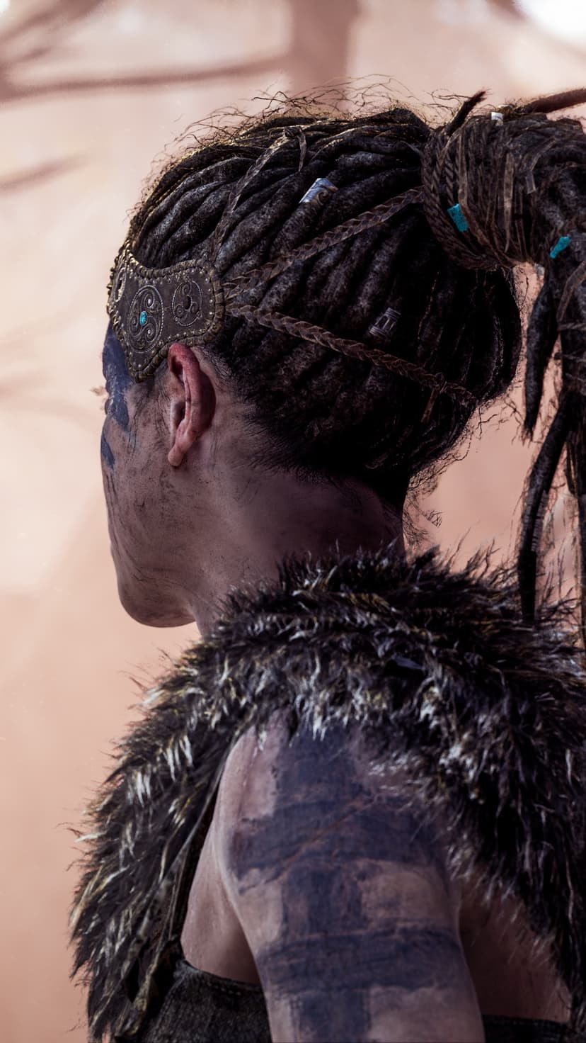 Side profile of a warrior with dreadlocks, blue face paint, and a fur mantle against a blurred background.