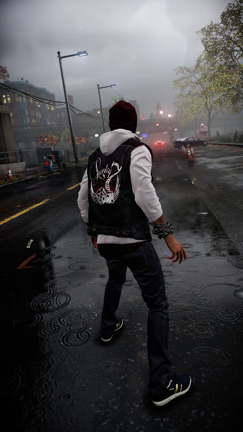 Delsin Rowe stands on a wet street in the rain wearing a denim vest and beanie, with ripples in puddles.