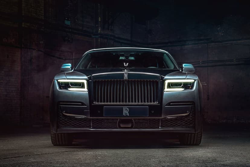 Rolls-Royce Ghost front view with glowing white LED headlights in a dark, industrial brick garage environment.
