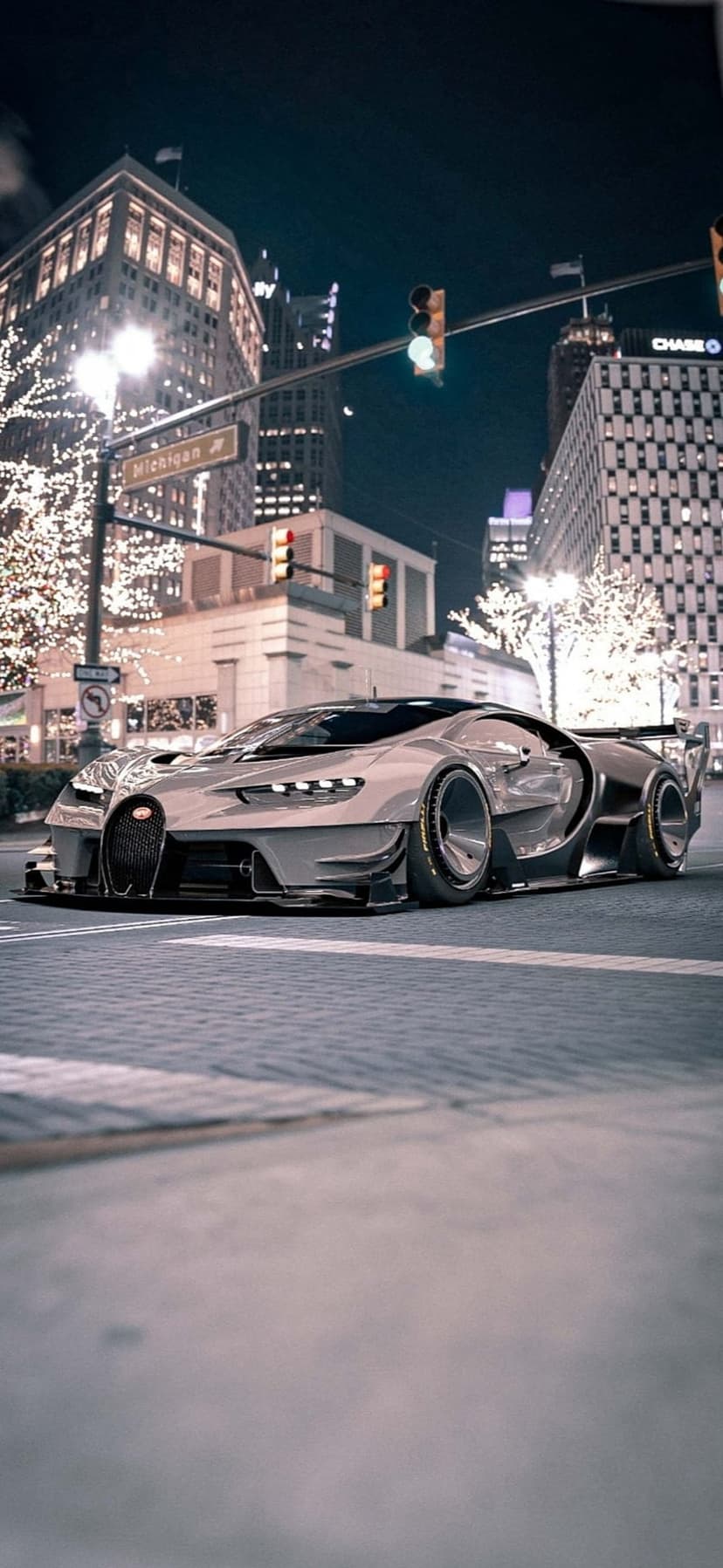 Grey Bugatti Chiron hypercar on a city street at night with glowing trees and urban architecture in the background.