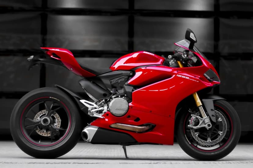 Red Ducati 1299 Panigale sportbike side profile view against a dark, blurred industrial garage background.