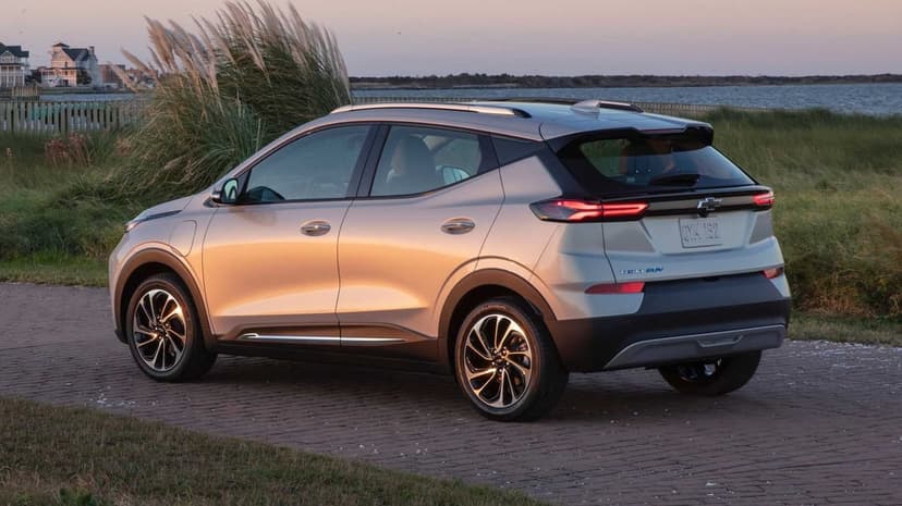 Silver Chevrolet Bolt EUV parked on a brick path near beach grass and water during a golden hour sunset.