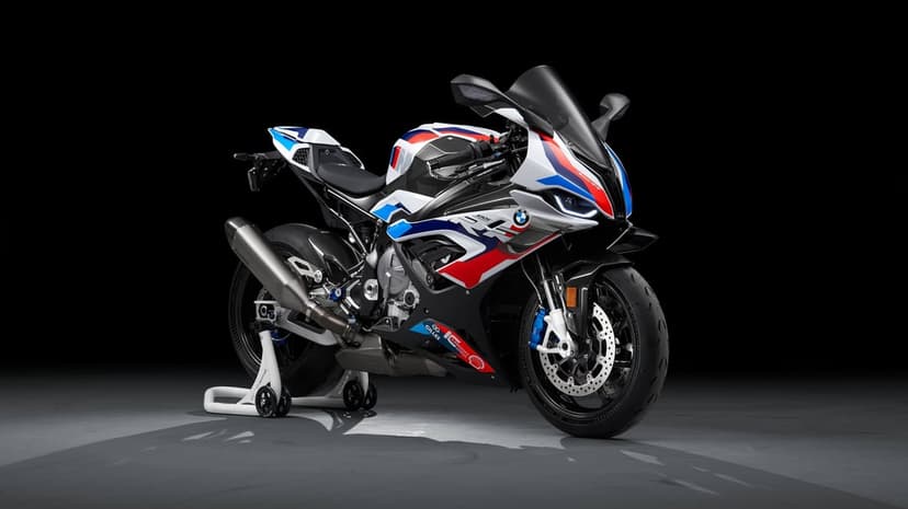 BMW M 1000 RR superbike with white, blue, and red racing livery on a paddock stand in a dark studio.
