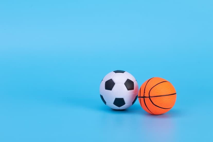 Soccer ball and orange basketball positioned on a bright blue background, showing detailed textures and colors.