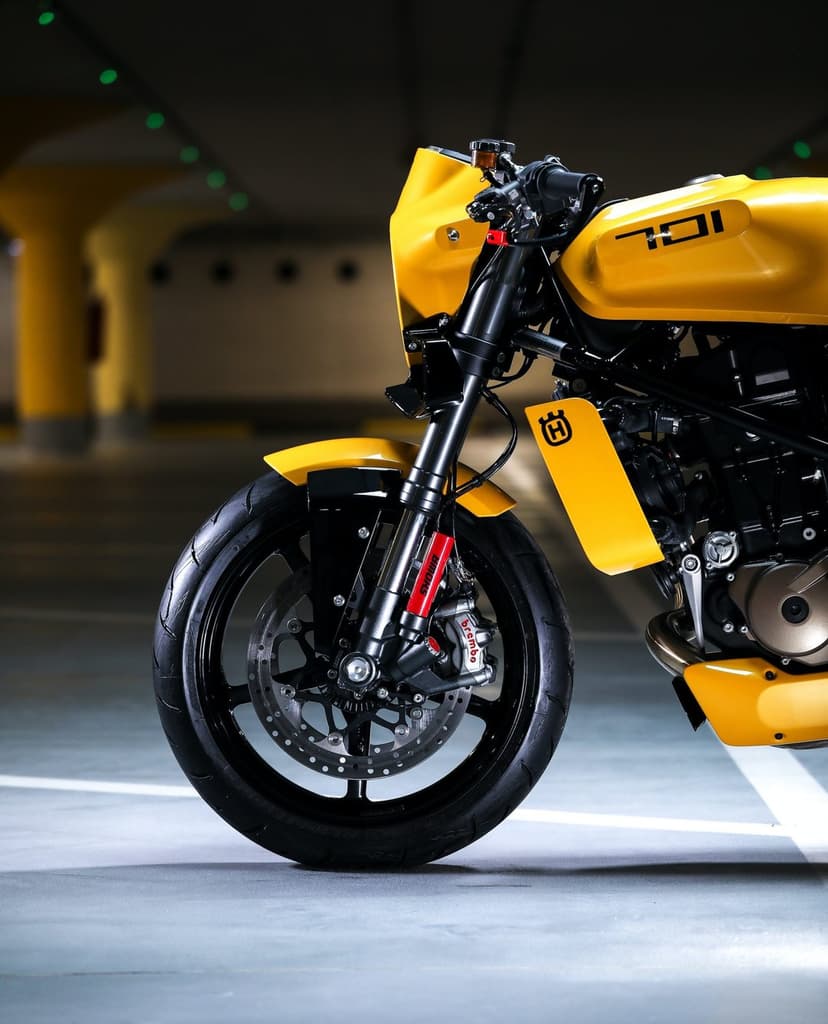 Close-up of a yellow Husqvarna 701 motorcycle with Brembo brakes and Showa forks in a dark parking garage.