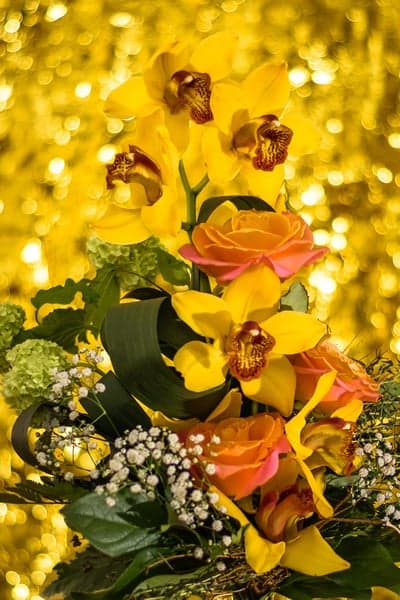 Vibrant yellow orchids and roses bouquet, golden bokeh background