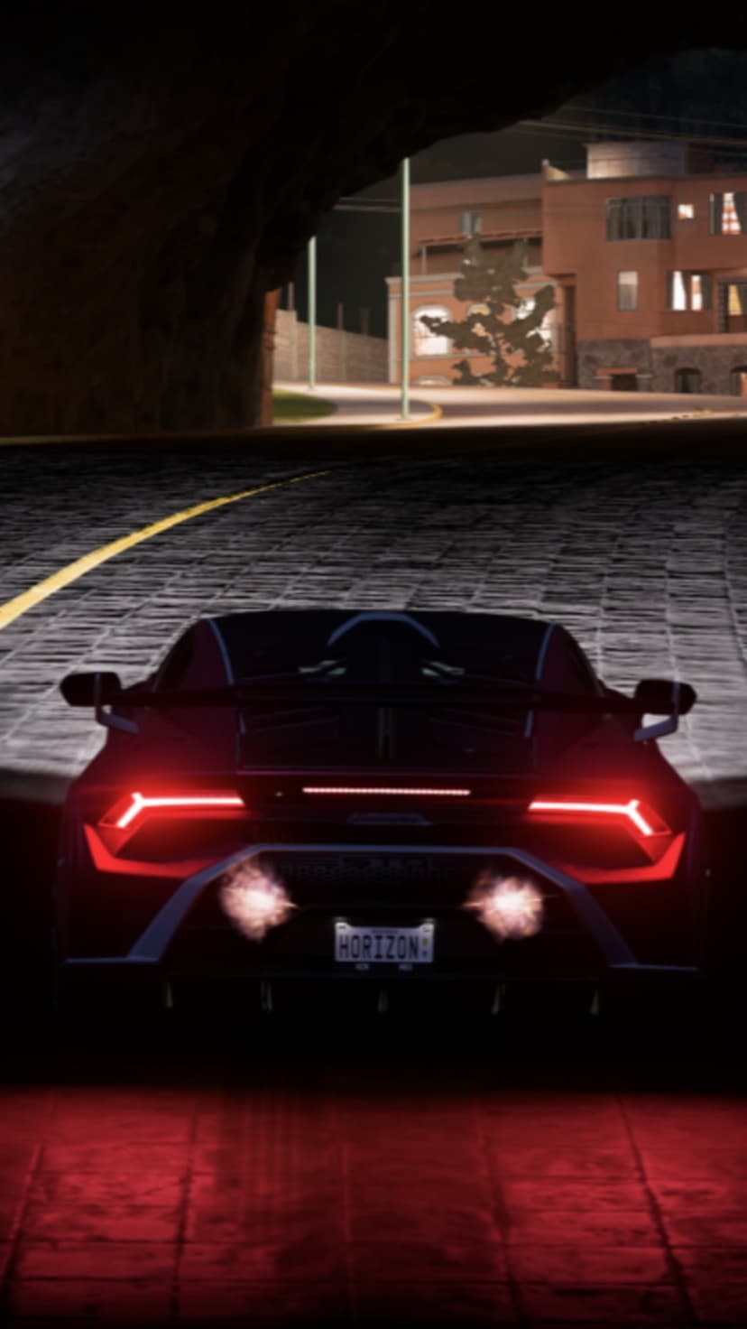 Red Lamborghini taillights illuminating a cobblestone road inside a dark tunnel at night under city lights.