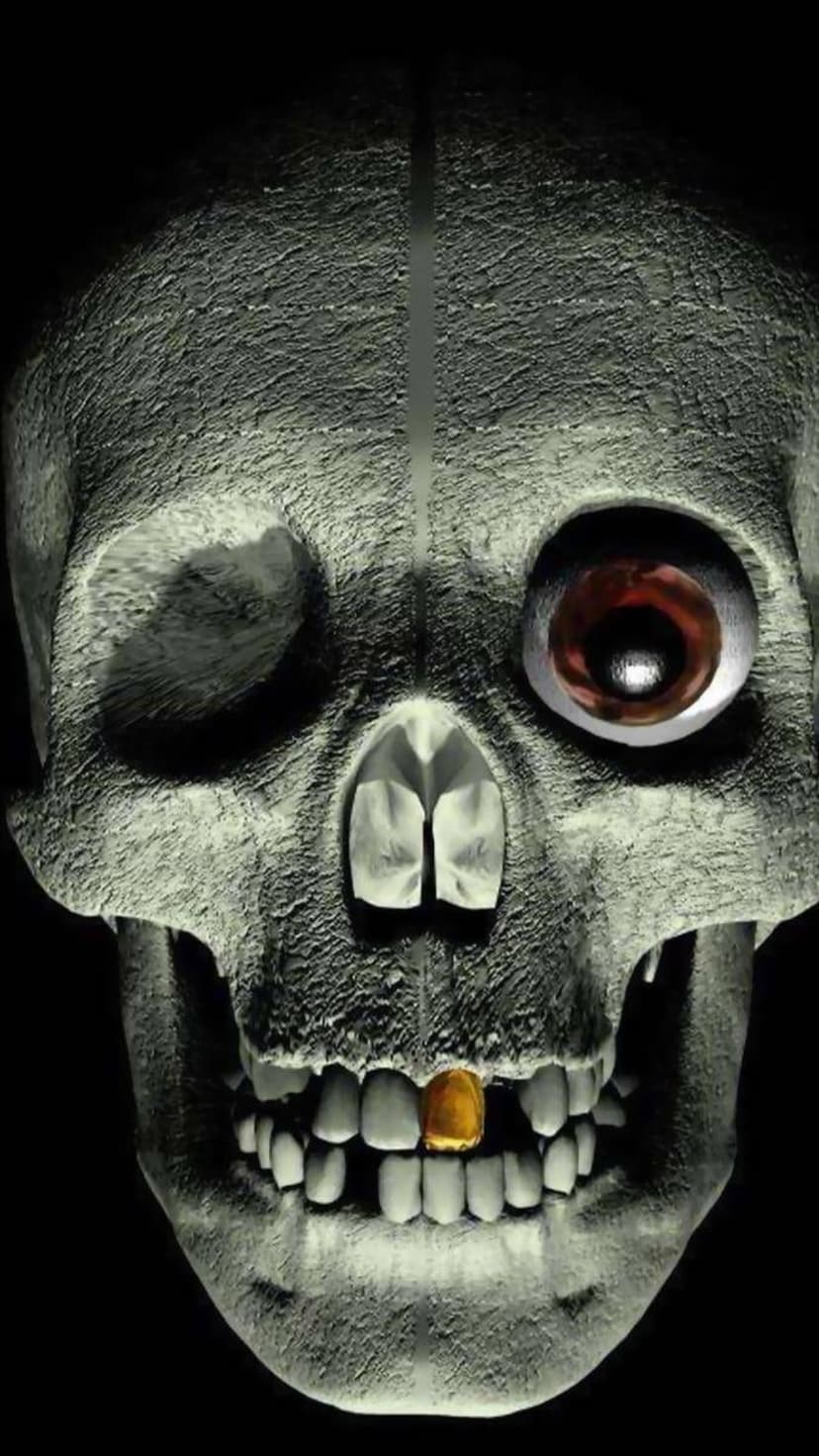 Human skull featuring a single gold tooth and one glowing red eye set against a dark shadowed background.