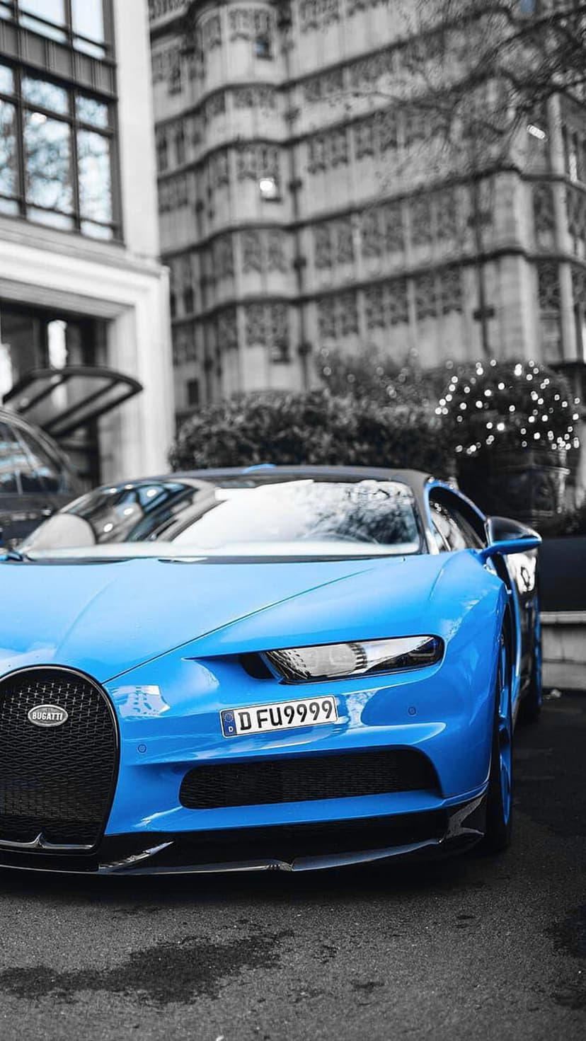 Blue Bugatti Chiron parked on a city street in front of a gray historic building with ornate architectural details.