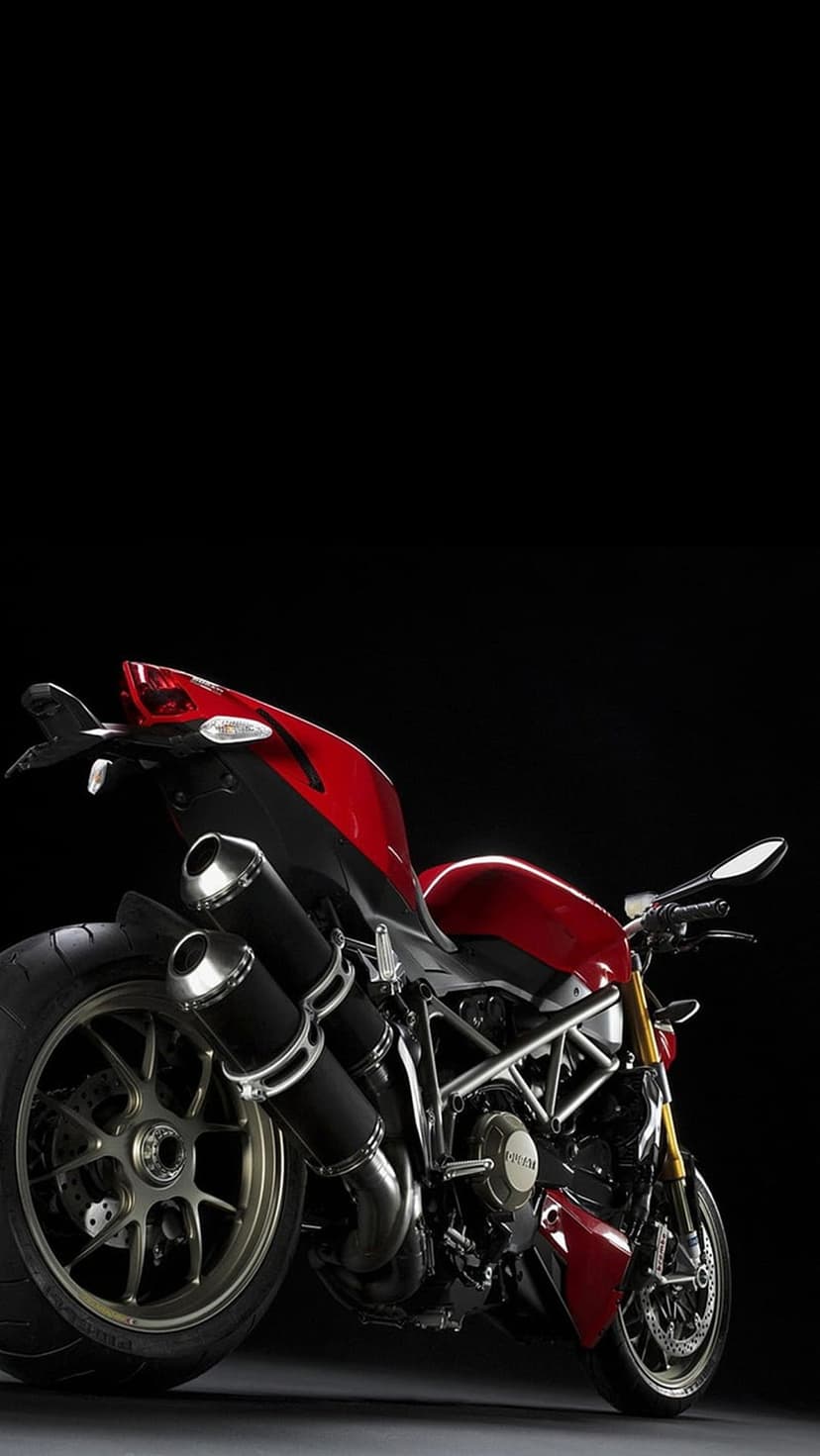 Red Ducati sportbike with visible exhaust pipes and engine details centered on a solid black studio background.