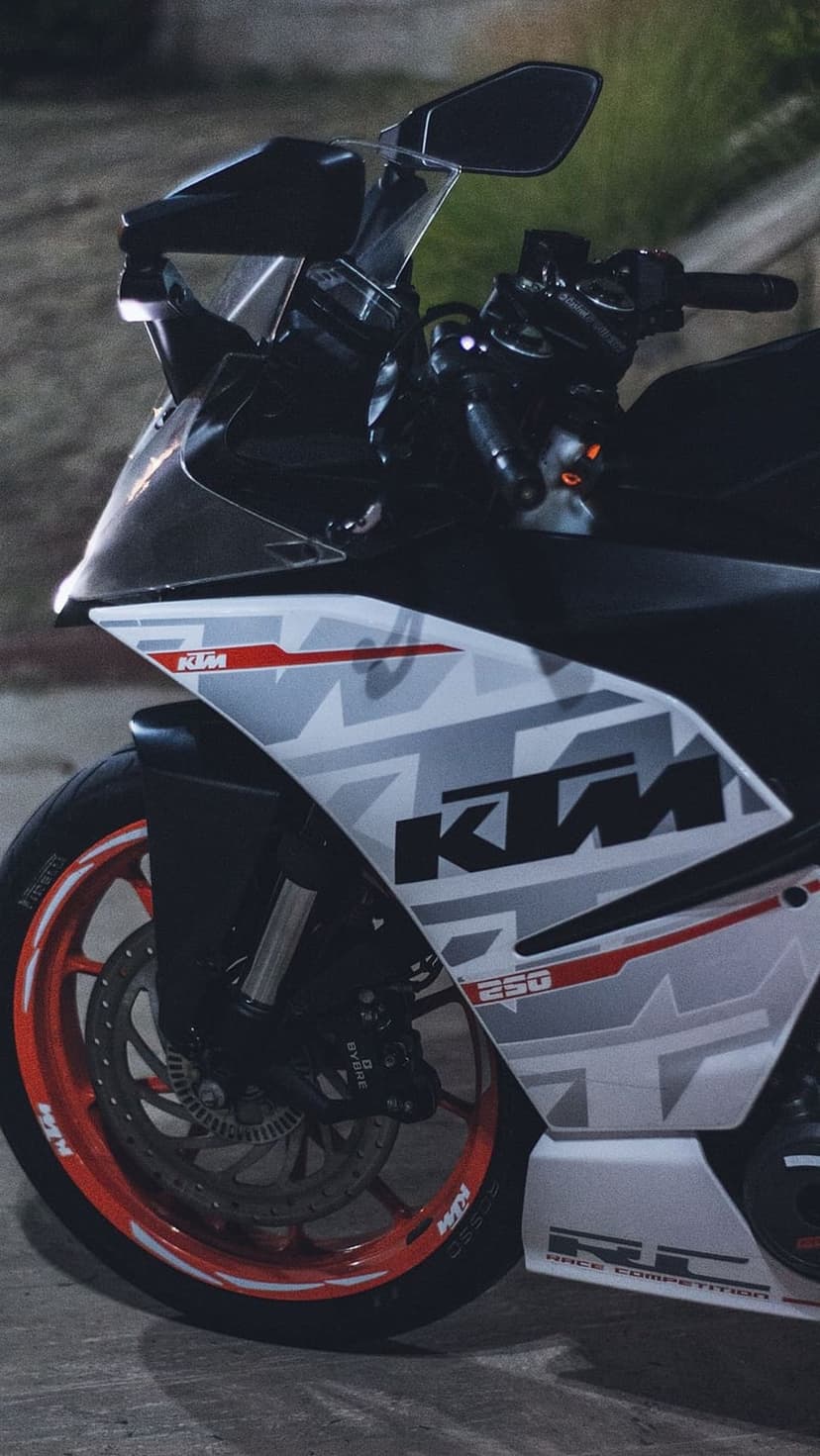 KTM RC 250 front wheel with orange rim and disc brake against a white and grey fairing in dramatic lighting.