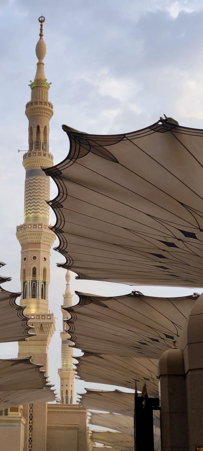 Towering minarets and large folding umbrellas overlook the white marble courtyard of the Prophet's Mosque in Medina.