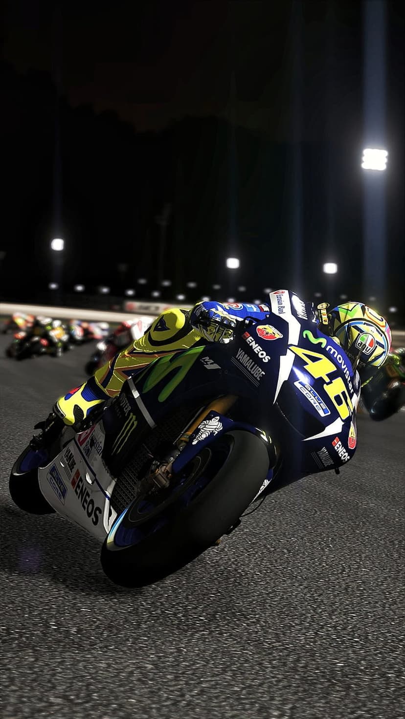 Valentino Rossi leans a blue Yamaha motorcycle into a sharp turn under glowing night track floodlights.