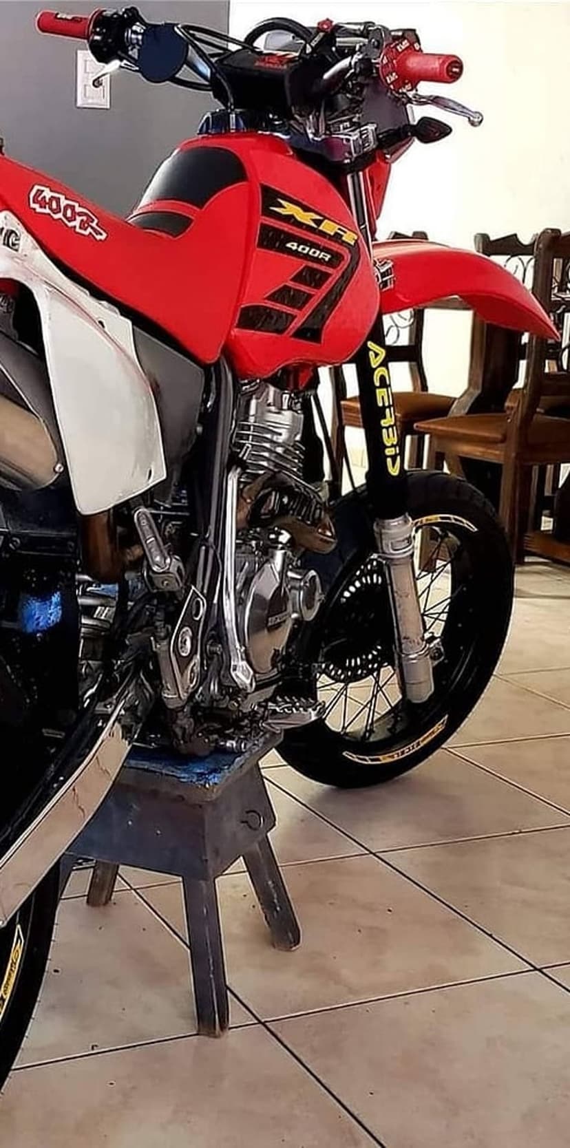 Honda XR400R motorcycle on a metal stand showing red fairings, engine details, and Acerbis fork guards inside.