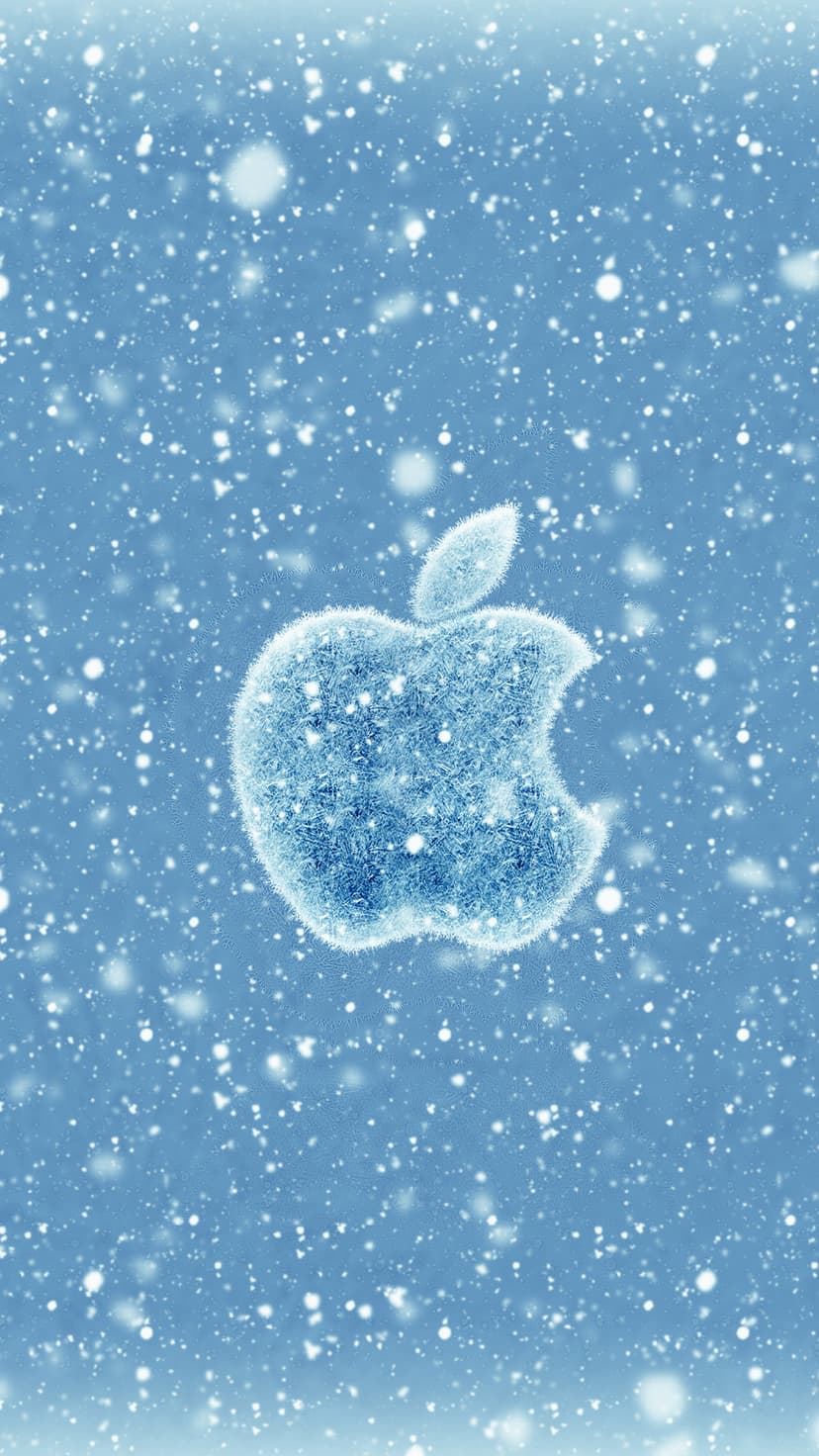 Apple logo made of shimmering ice crystals sits against a blue sky with soft, out-of-focus falling snowflakes.