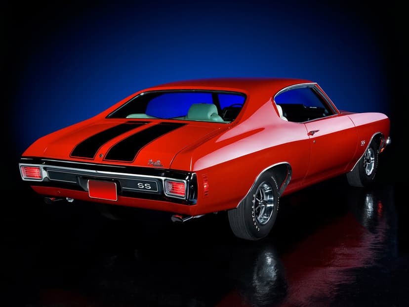 Red 1970 Chevrolet Chevelle SS with black racing stripes on a reflective black floor with blue background.
