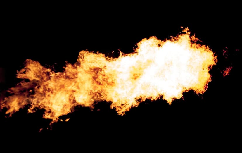 Intense orange and white flames erupting vertically against a solid black background with wispy smoke details.