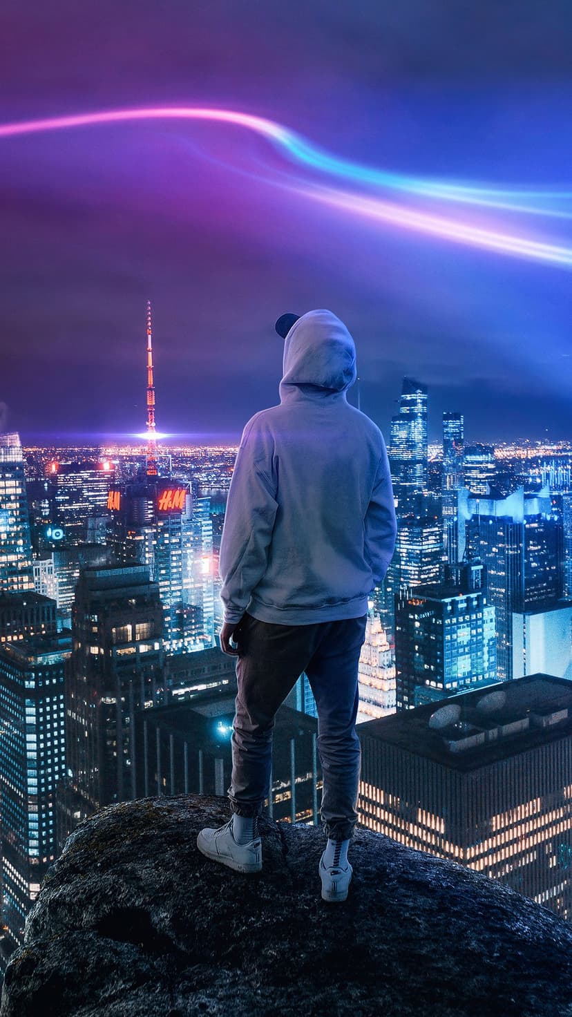 Hooded figure stands on a rocky cliff overlooking a glowing neon city with pink and blue light trails in the sky.