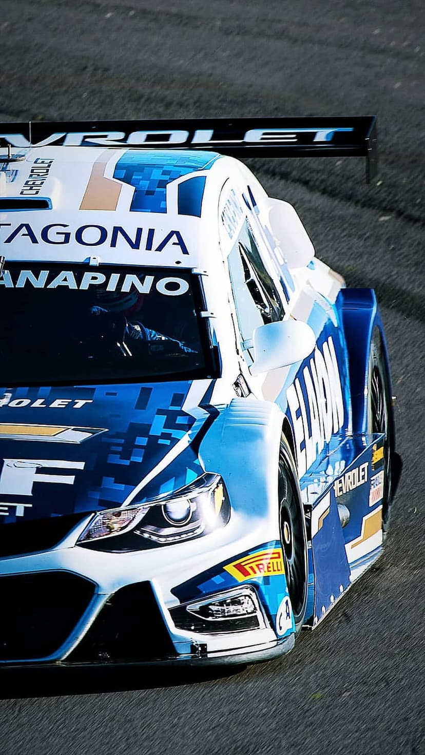 Chevrolet racing car with blue and white Patagonia livery accelerates on a track with visible Pirelli tires.