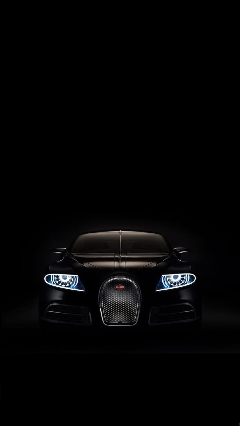 Black Bugatti Veyron with illuminated quad headlights and horseshoe grille centered against a dark background.