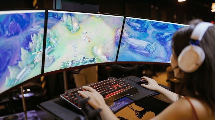 Woman gamer using triple monitors and backlit mechanical keyboard in a dark room with soft ambient lighting.