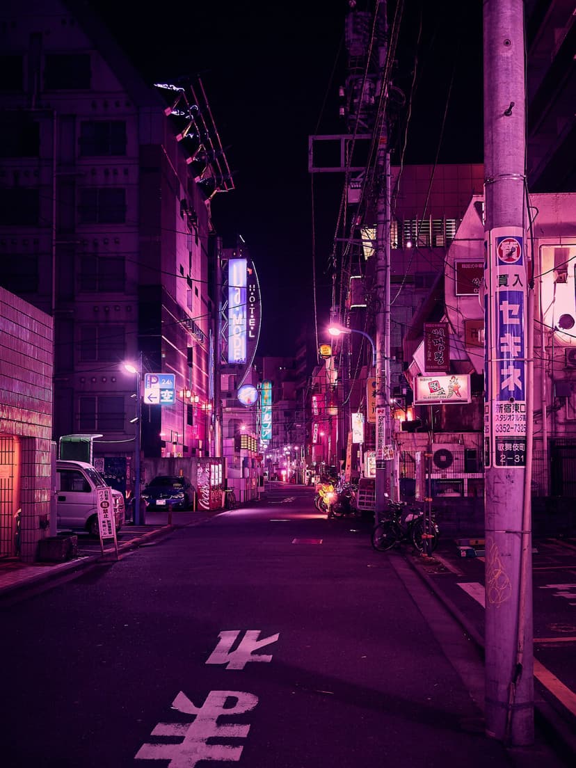 Purple and pink neon signs hang above a dark Tokyo street with tangled overhead wires and wet pavement.