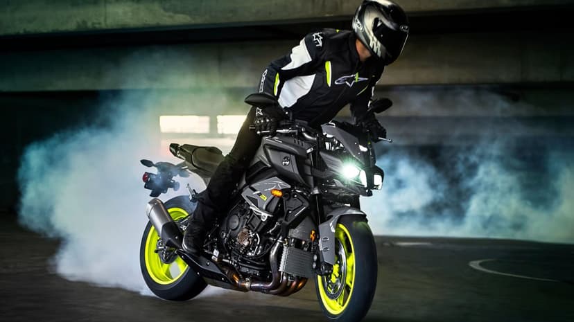 Motorcyclist on a Yamaha MT-10 performing a burnout with neon yellow wheels and swirling white tire smoke.