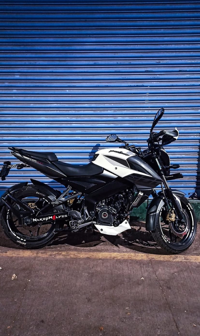 White and black sport motorcycle parked in front of a blue corrugated roller door in vertical orientation.