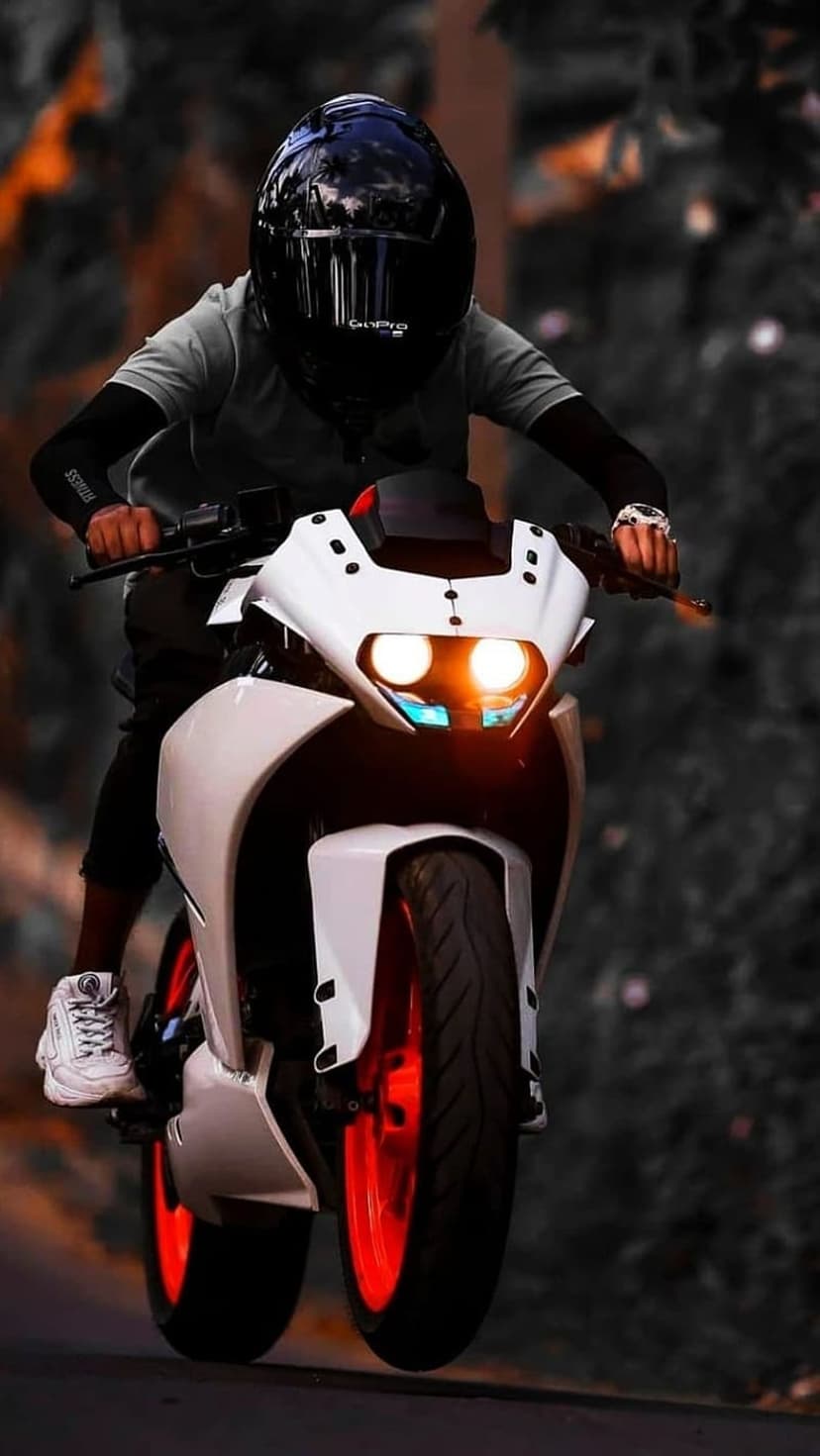 Motorcyclist in a black helmet rides a white sportbike with vibrant orange wheels against a blurred background.